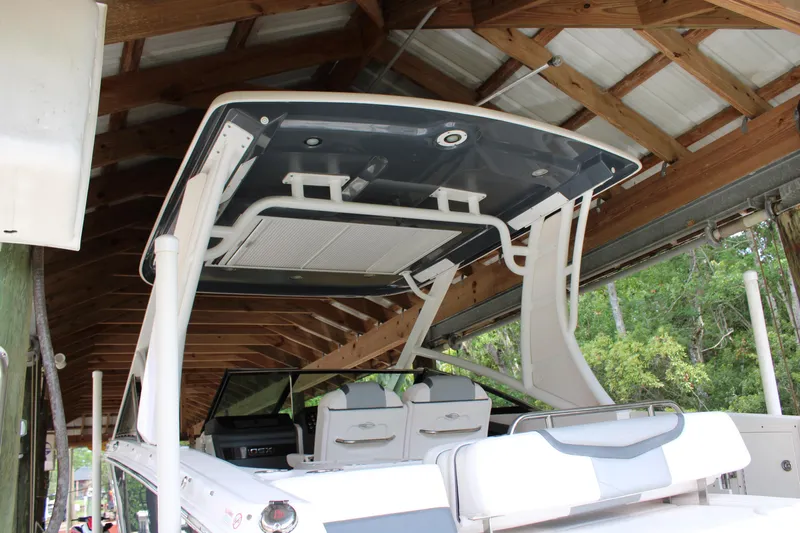  Yacht Photos Pics 2021 Chaparral 280 OSX boat under a wooden shelter, showcasing its sleek design and seating area.