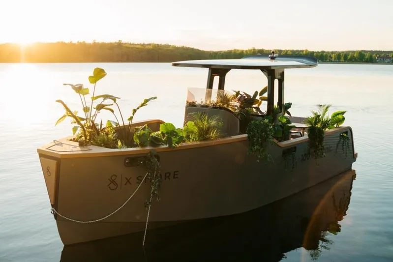  Yacht Photos Pics 2023 X Shore Eelex 8000 electric boat with plants, on a serene lake at sunset.