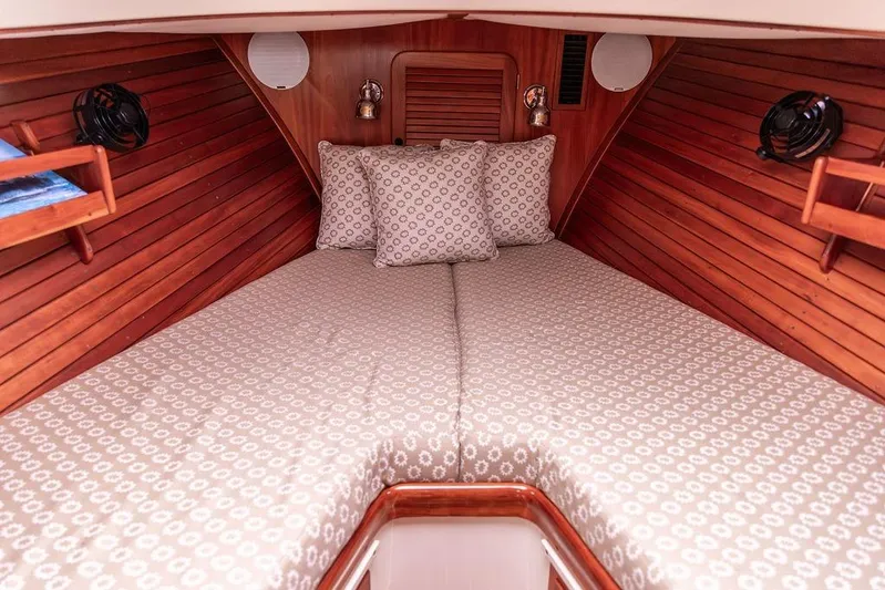 Zuzu Yacht Photos Pics 2004 Hinckley Picnic Boat EP cabin interior with cozy bedding and wooden paneling.