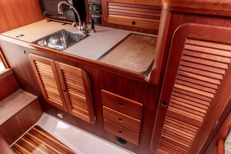 Zuzu Yacht Photos Pics 2004 Hinckley Picnic Boat EP interior with wooden cabinetry and stainless steel sink.