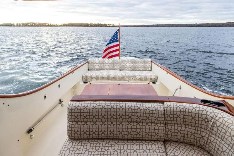 Zuzu Yacht Photos Pics 2004 Hinckley Picnic Boat EP with American flag, elegant seating, and scenic water view.