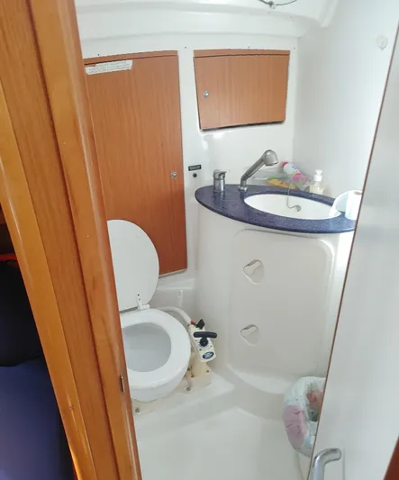Blue Nomade Yacht Photos Pics 2006 Beneteau Cyclades 50.4 yacht bathroom with toilet, sink, and wooden cabinets.