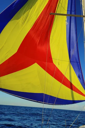 Blue Nomade Yacht Photos Pics Colorful sail of a 2006 Beneteau Cyclades 50.4 yacht against a clear blue sky.