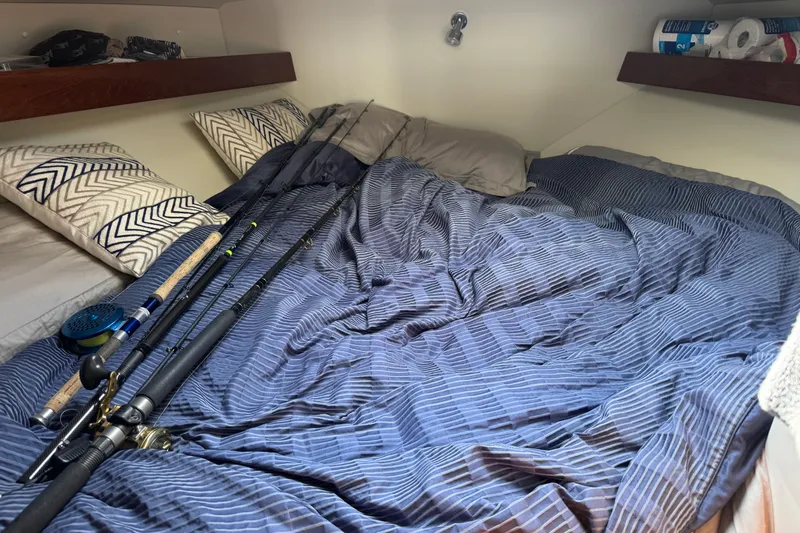  Yacht Photos Pics Cozy cabin interior of 2017 Ocean Sport Roamer with fishing rods on striped bedding.