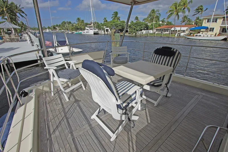 Just Right Yacht Photos Pics 2004 Dettling Express Cruiser deck with chairs and table, overlooking a scenic waterfront.