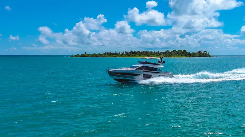 Salina Yacht Photos Pics 2024 Azimut S7 yacht cruising on turquoise waters near a tropical island under a blue sky.