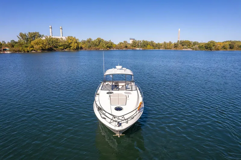  Yacht Photos Pics 2009 Regal Commodore 4060 yacht on calm water, surrounded by trees and industrial structures.