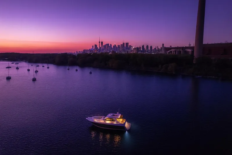  Yacht Photos Pics 2009 Regal Commodore 4060 yacht on serene water at sunset, city skyline in background.