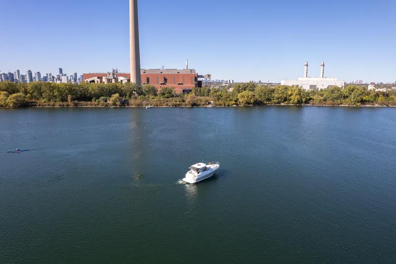  Yacht Photos Pics A 2009 Regal Commodore 4060 yacht cruising on a calm river with industrial buildings in the background.