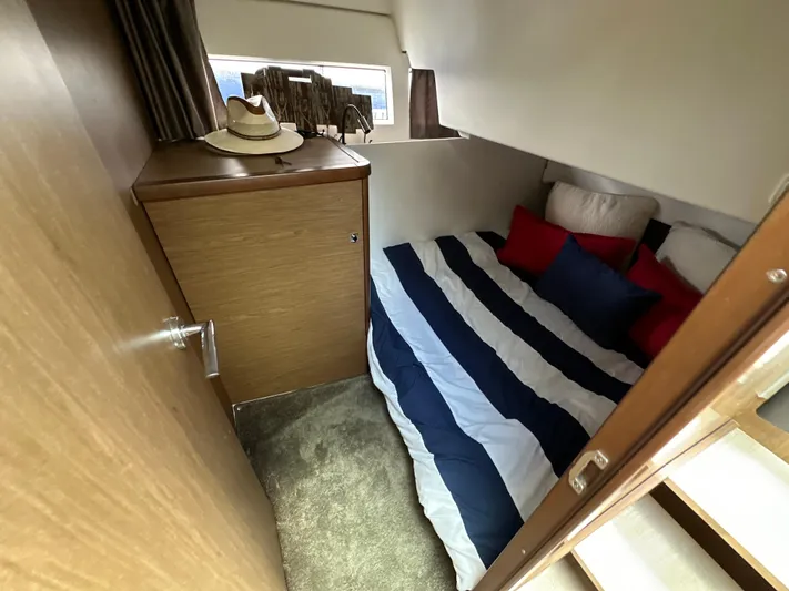 Andalucia Yacht Photos Pics 2017 Jeanneau NC 11 cabin with striped bedding and wooden cabinetry.