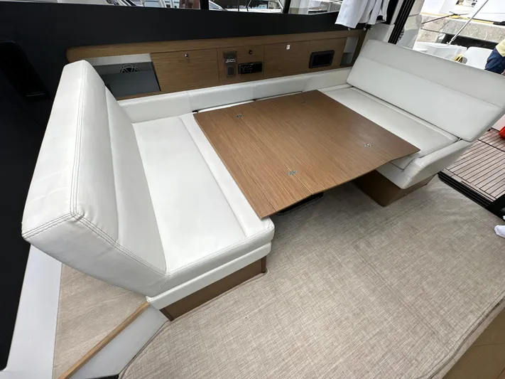 Andalucia Yacht Photos Pics 2017 Jeanneau NC 11 interior with white seating and wooden table.