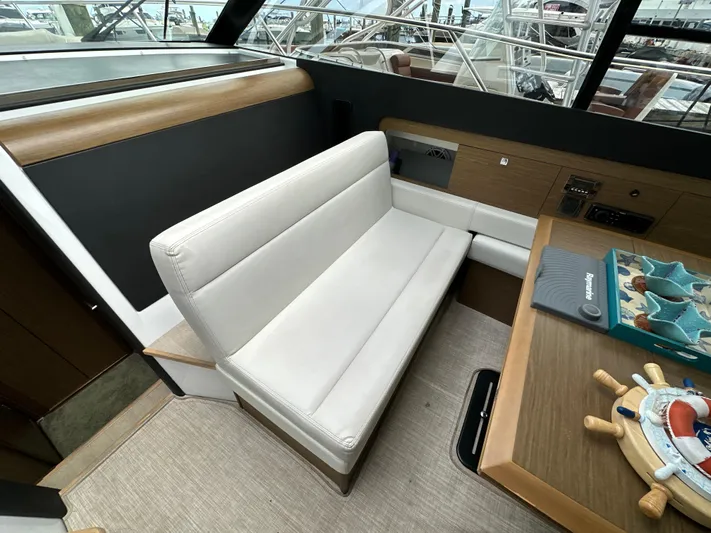 Andalucia Yacht Photos Pics Interior of 2017 Jeanneau NC 11 boat with white seating and wooden table.