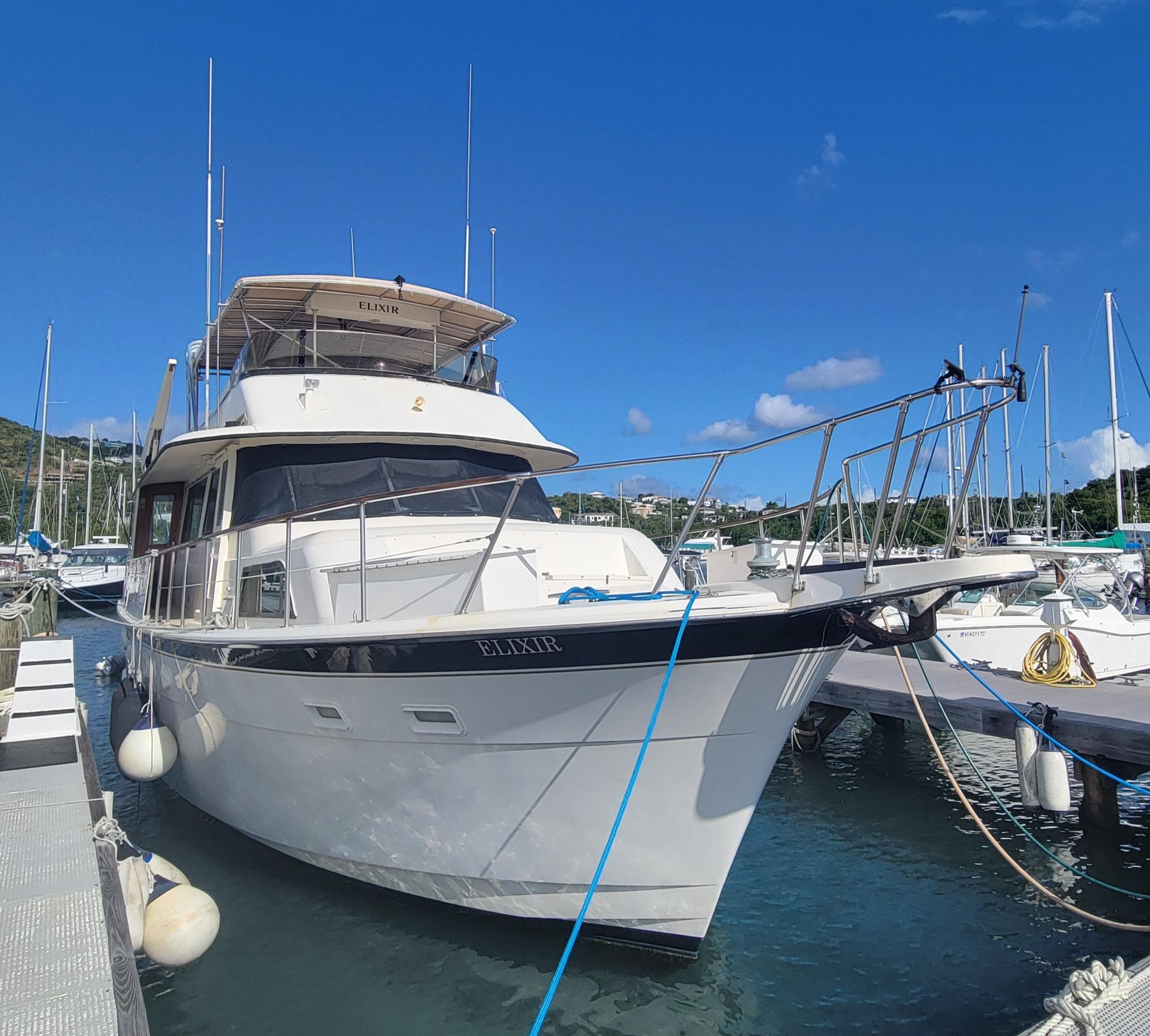1982 Hatteras 56 Wide Body yacht docked in a marina under clear blue skies.