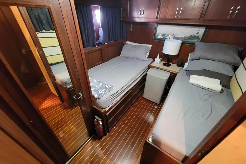 'elixir' Yacht Photos Pics 1982 Hatteras 56 Wide Body cabin with twin beds, wooden interior, and nautical decor.