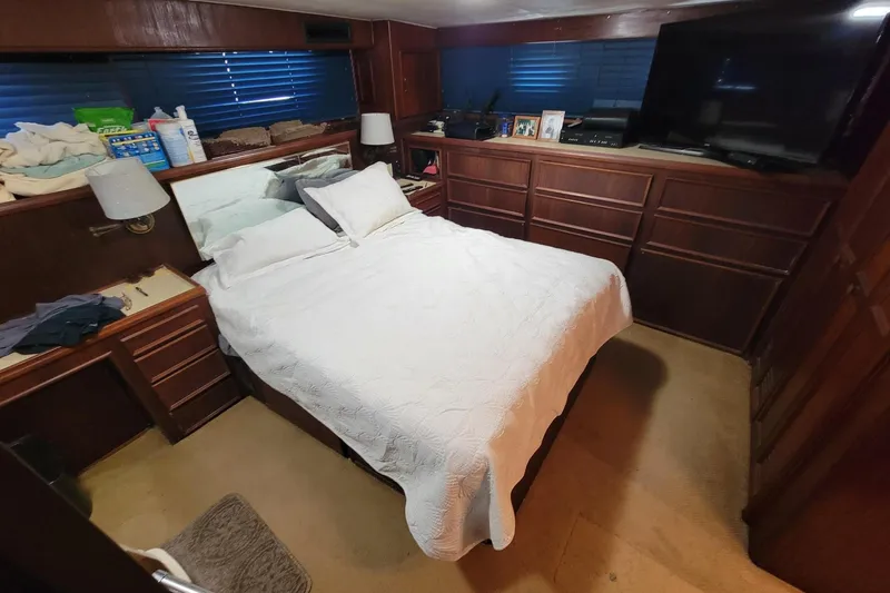 'elixir' Yacht Photos Pics Cozy bedroom in 1982 Hatteras 56 Wide Body yacht with wood paneling and a TV.