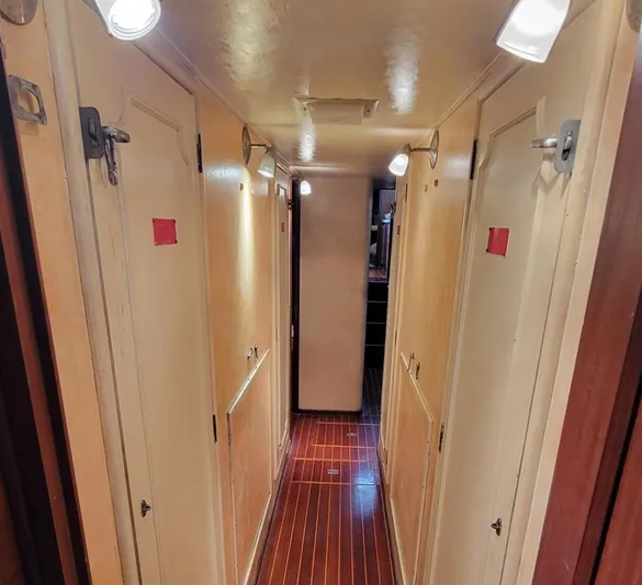 'elixir' Yacht Photos Pics Narrow hallway inside 1982 Hatteras 56 Wide Body yacht with wooden flooring and multiple doors.