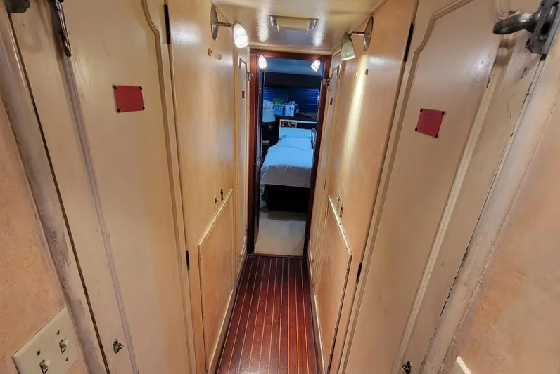 'elixir' Yacht Photos Pics Narrow hallway inside 1982 Hatteras 56 Wide Body yacht, featuring wooden flooring and cabin doors.