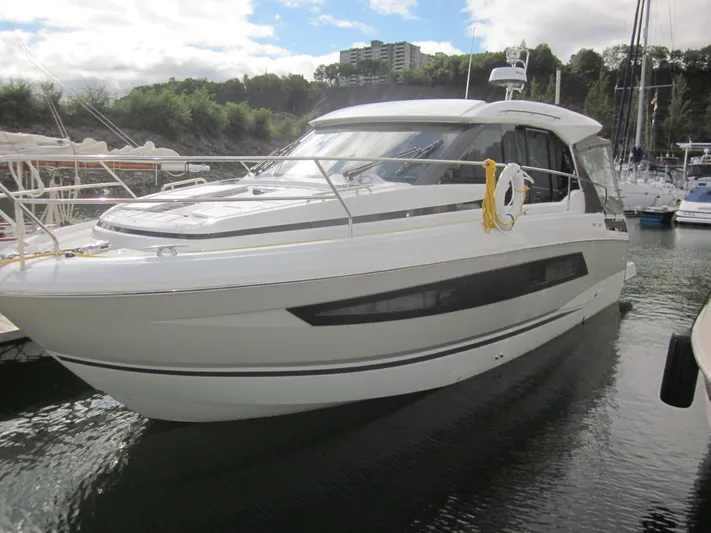  Yacht Photos Pics 2019 Jeanneau NC 33 yacht docked in a marina, surrounded by trees and buildings.
