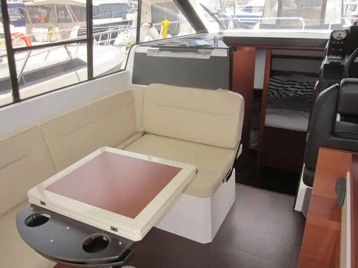  Yacht Photos Pics 2019 Jeanneau NC 33 interior with beige seating, table, and cabin view.