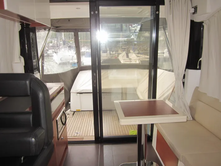  Yacht Photos Pics Interior of 2019 Jeanneau NC 33 yacht with seating and table, overlooking marina.