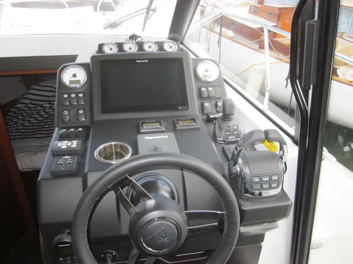  Yacht Photos Pics Control panel of a 2019 Jeanneau NC 33 boat with steering wheel and navigation equipment.