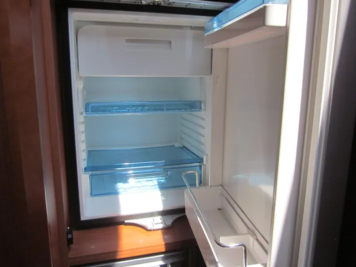  Yacht Photos Pics Open refrigerator inside 2019 Jeanneau NC 33 boat, showing empty shelves and door compartments.