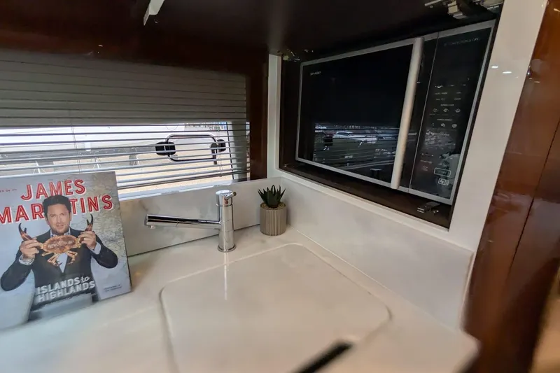 Tender Garage & Hi/lo Swimplatform Yacht Photos Pics Fairline Targa 45 GT 2022 yacht kitchen with microwave, sink, and cookbook display.