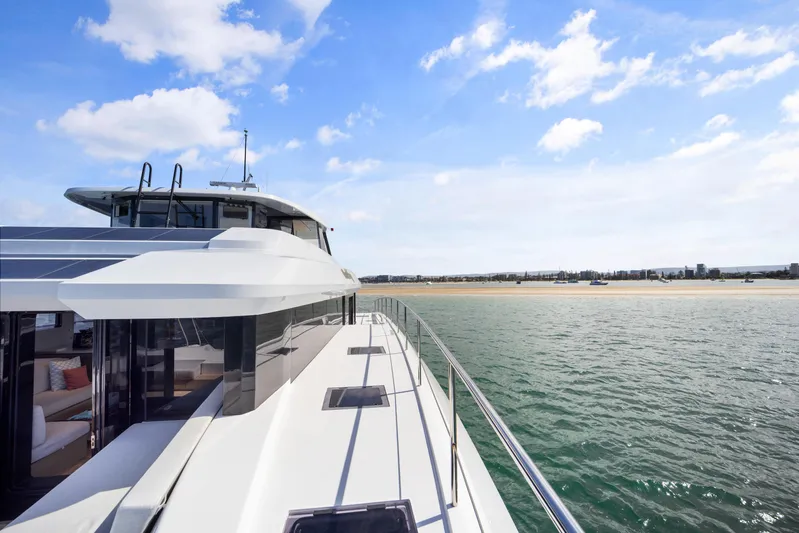 Bundalong Yacht Photos Pics 2023 McConaghy MC 82P yacht cruising near a sandy shoreline under a clear blue sky.