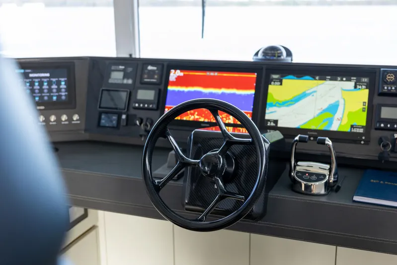 Bundalong Yacht Photos Pics Control panel of 2023 McConaghy MC 82P yacht with navigation screens and steering wheel.