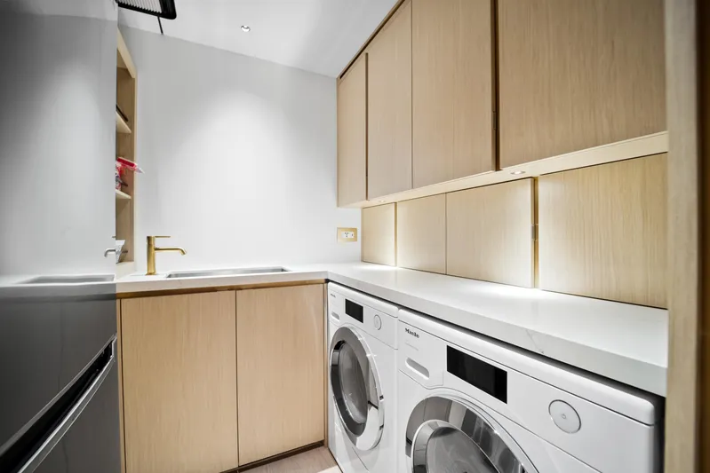 Bundalong Yacht Photos Pics Modern laundry room with wooden cabinets, washer, dryer, and sleek sink. McConaghy MC 82P, 2023.