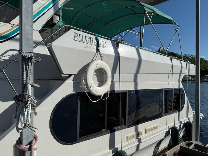 Lexy Lu Yacht Photos Pics 1996 Bluewater Yachts 52 Limited Edition with green canopy and lifebuoy, docked by the water.