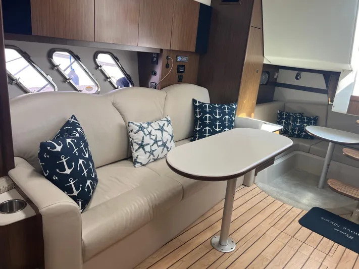 Knot A Care Yacht Photos Pics Interior of 2015 Cruisers Yachts 350 Express with nautical-themed cushions and wooden flooring.