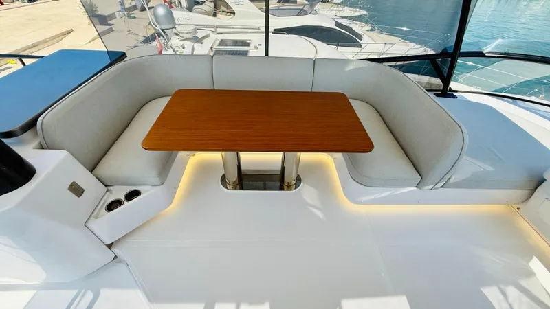  Yacht Photos Pics Luxurious seating area on 2025 Azimut Magellano 60 yacht with wooden table and cushioned seats.