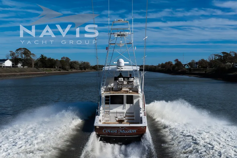 Covert Mission Yacht Photos Pics 1998 Viking 58 Convertible yacht cruising on a scenic waterway under a clear blue sky.