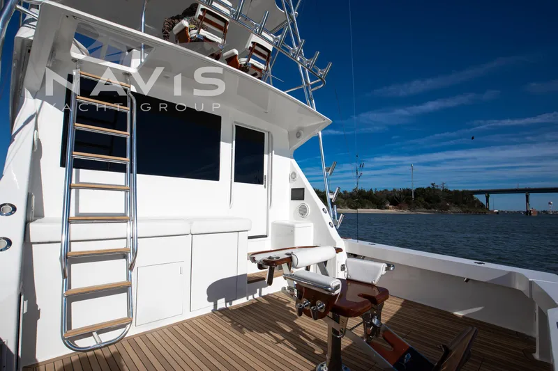 Covert Mission Yacht Photos Pics 1998 Viking 58 Convertible yacht deck with fishing chair and ladder, under clear blue sky.