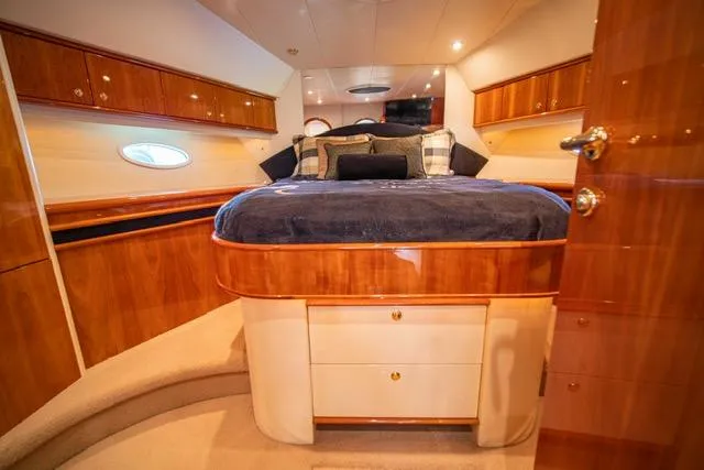  Yacht Photos Pics Luxurious 2005 Neptunus 62 Flybridge yacht bedroom with elegant wood finish and cozy bedding.