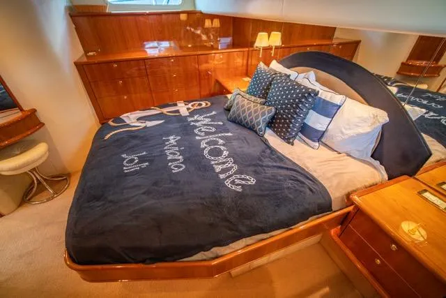  Yacht Photos Pics Luxurious 2005 Neptunus 62 Flybridge yacht bedroom with elegant bedding and wooden cabinetry.