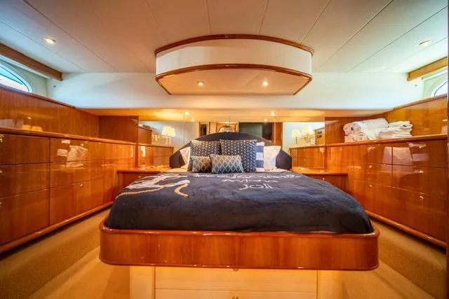  Yacht Photos Pics Luxurious 2005 Neptunus 62 Flybridge yacht bedroom with elegant wood finishes and plush bedding.