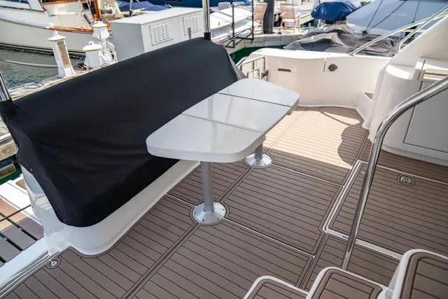  Yacht Photos Pics Neptunus 62 Flybridge 2005 yacht deck with seating and table, docked at marina.