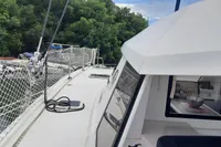 Nautitech 40 Open catamaran, 2014 model, docked near lush greenery and other boats.