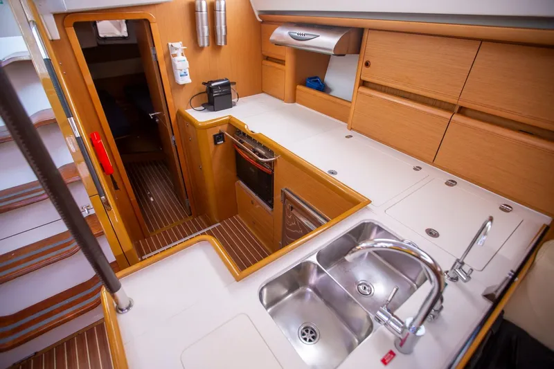 Amelie Yacht Photos Pics Modern kitchen interior of 2011 Jeanneau 57 yacht with wooden cabinetry and dual sink.