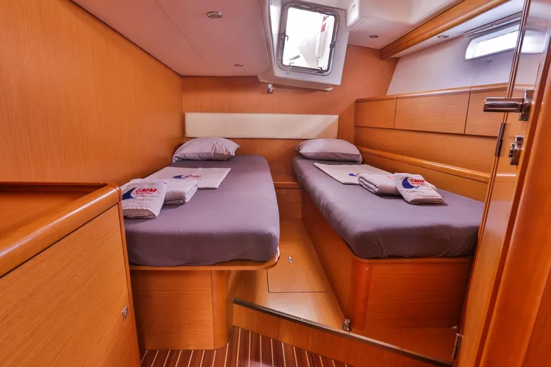 Amelie Yacht Photos Pics Twin cabin interior of 2011 Jeanneau 57 yacht with wooden finish and cozy bedding.