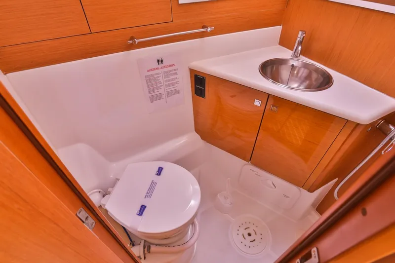 Amelie Yacht Photos Pics 2011 Jeanneau 57 yacht bathroom with sink and toilet, featuring wooden cabinetry.