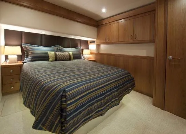  Yacht Photos Pics Manufacturer Provided Image: Luxurious bedroom interior of 2013 Hatteras GT54 yacht with striped bedding and wooden cabinets.