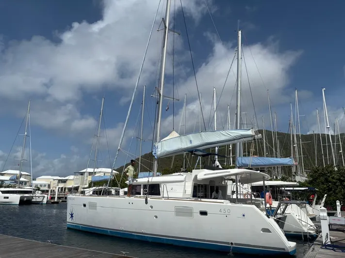 King Lewis Yacht Photos Pics 2016 Lagoon 450 catamaran docked at marina under blue sky.