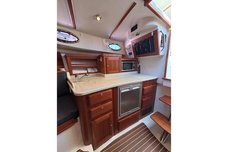 Hannah E Yacht Photos Pics 2018 Back Cove 30 yacht interior with kitchenette, featuring wood cabinetry and modern appliances.