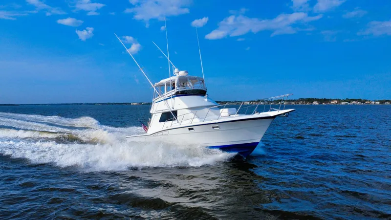 Reel Amnesia Yacht Photos Pics 1984 Hatteras 36 Convertible cruising on open water under a clear blue sky.