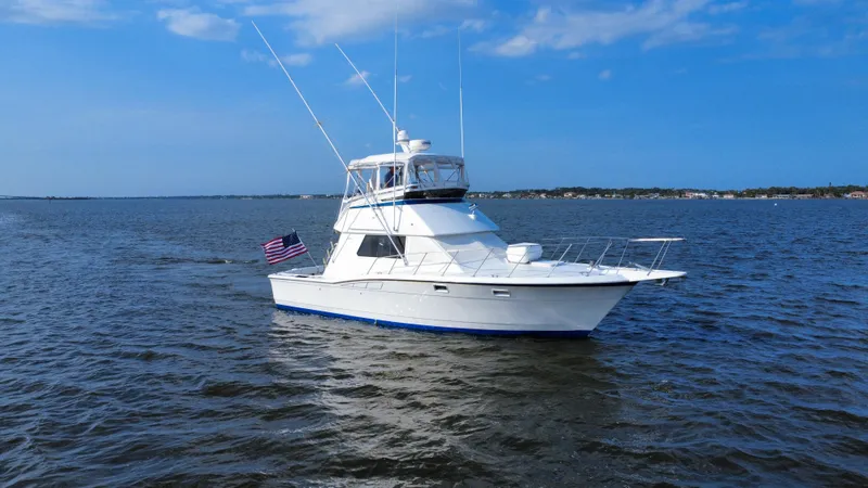 Reel Amnesia Yacht Photos Pics 1984 Hatteras 36 Convertible yacht cruising on open water under a clear blue sky.