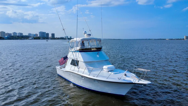 Reel Amnesia Yacht Photos Pics 1984 Hatteras 36 Convertible yacht on open water with city skyline in background.