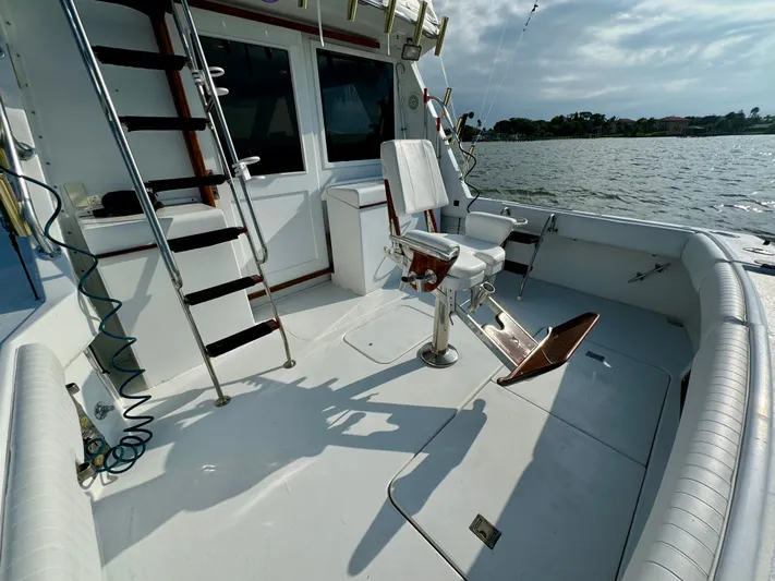 Reel Amnesia Yacht Photos Pics 1984 Hatteras 36 Convertible boat deck with fishing chair and ladder, overlooking water.
